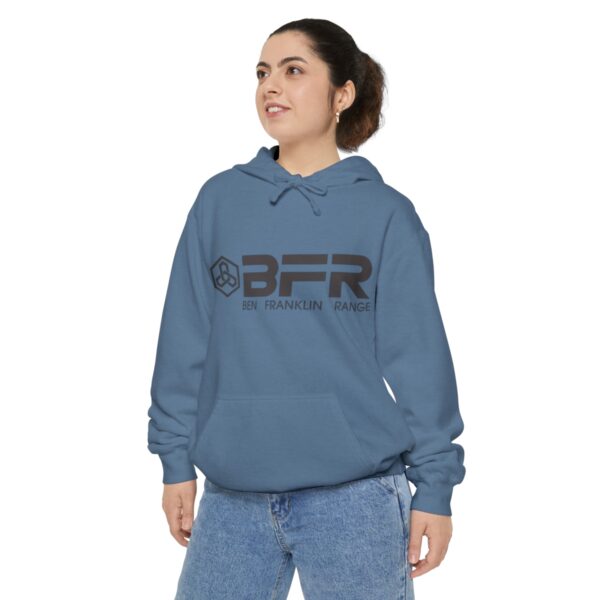 A woman wearing a BFR Logo - Unisex Garment-Dyed Hoodie hoodie with the word bfr on it.