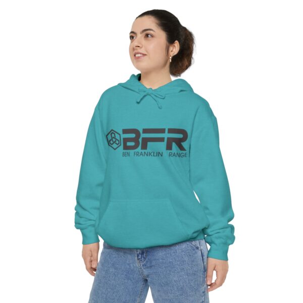 A woman wearing a turquoise BFR Logo - Unisex Garment-Dyed Hoodie with the word bfr on it.