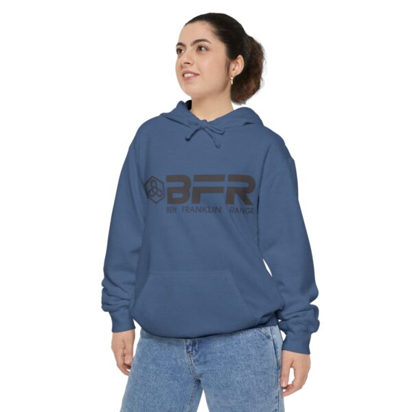 A woman wearing a blue BFR Logo - Unisex Garment-Dyed Hoodie with the word bfr on it.
