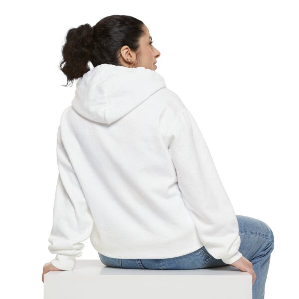 A woman wearing a BFR Logo - Unisex Garment-Dyed Hoodie and jeans sitting on a white box.