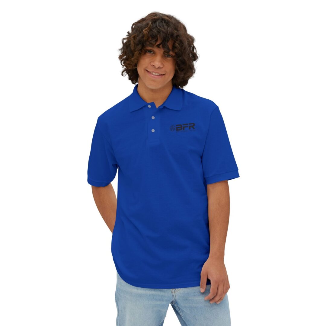 Young man in blue polo shirt smiling.