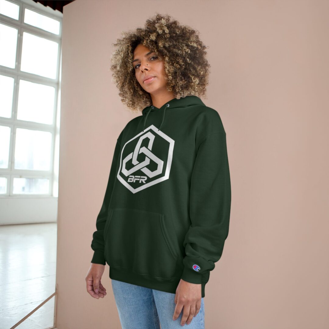 Person wearing green geometric-logo hoodie indoors.