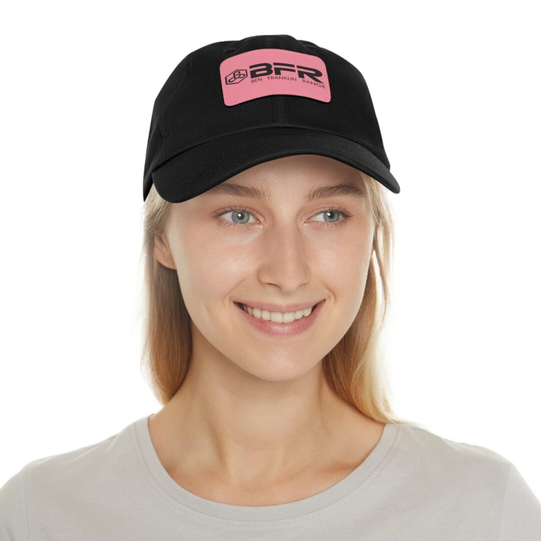 Smiling person wearing black cap with logo.