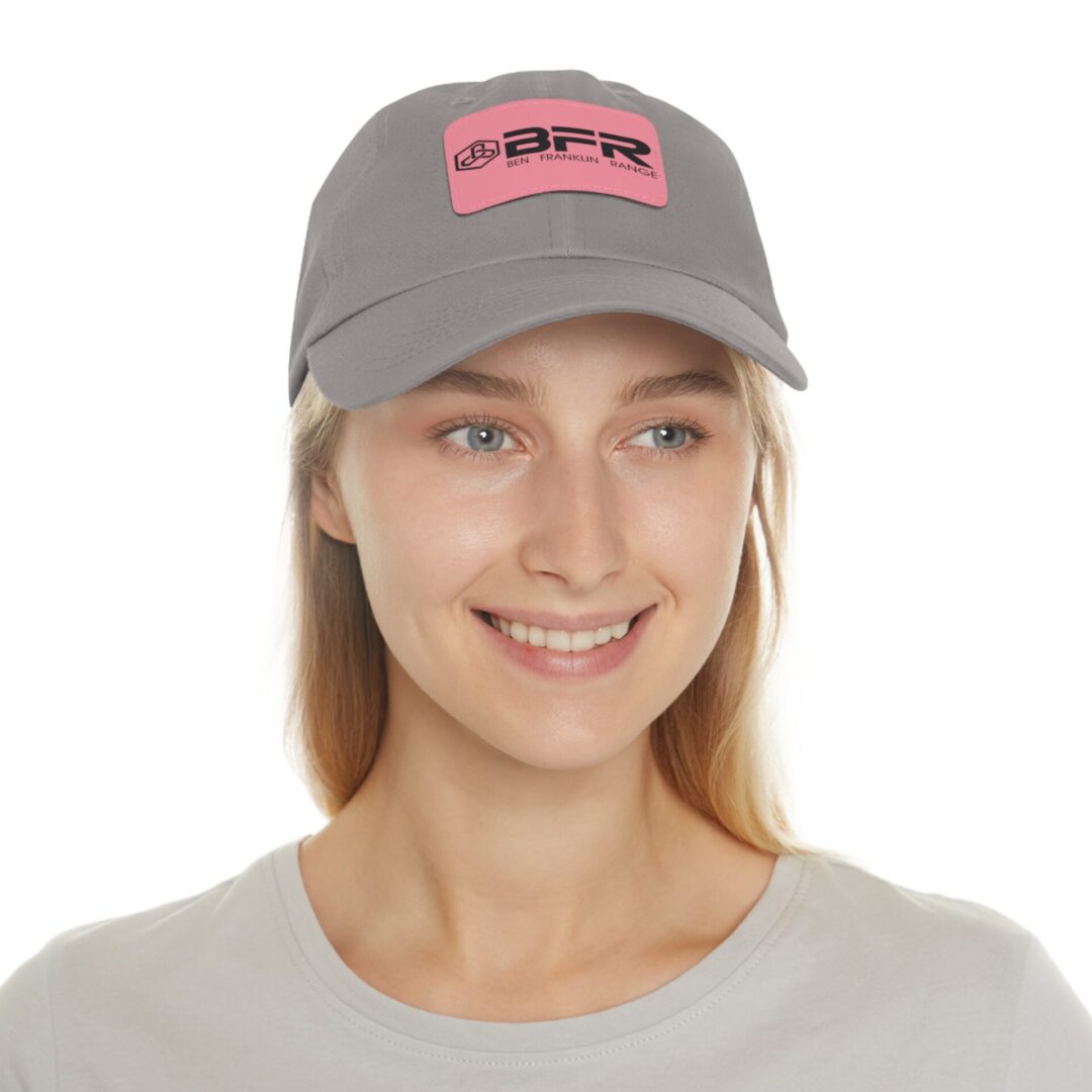 Person wearing gray cap with pink logo.