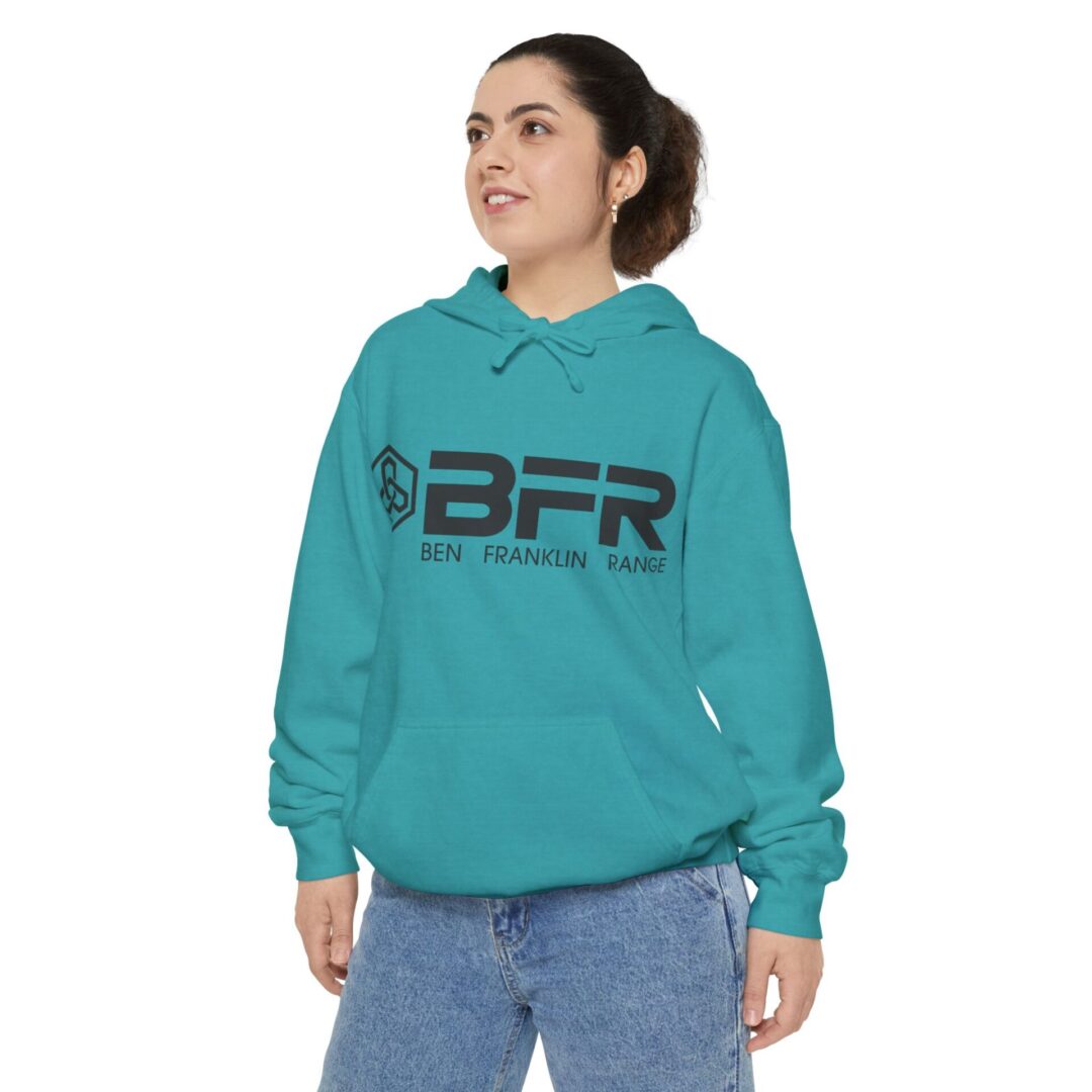 Woman wearing teal hoodie, posing confidently.